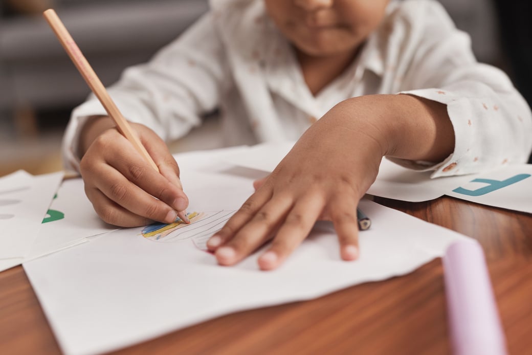 Close-Up Shot of a Kid Drawing on a Paper Using a Colored Pencil